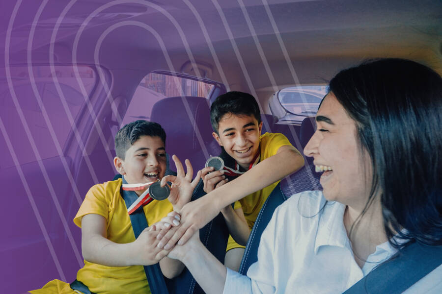 Parent and two children in the car after a game with medals